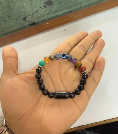 Hand holding a ZARAGRACE 9 Chakra bracelet with glossy black beads and colorful healing stones like Evil Eye, Citrine, Red Jasper, and African Turquoise